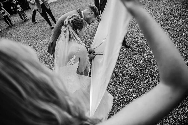 Brautpaar zerschneidet Bettlaken auf dem ein Herz gemalt ist.