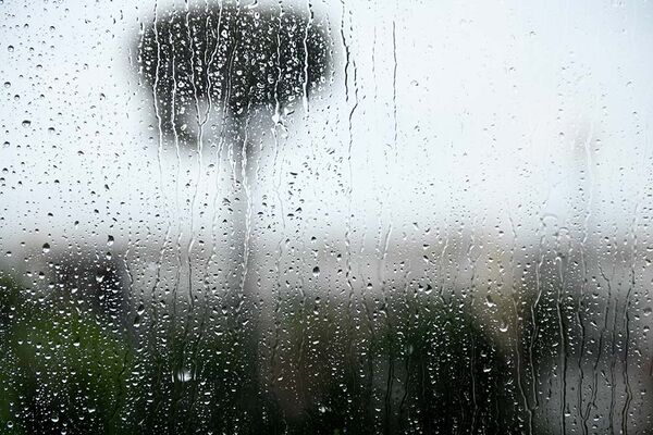 Das Bild zeigt Regentropfen auf einem Fenster. Die Schärfe liegt auf den Tropfen, der Hintergrund ist unscharf.