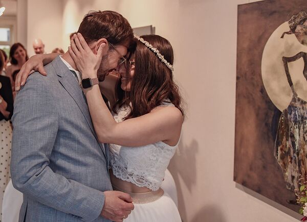 Brautpaar umarmen sich, Stirn an Stirn und lächeln sich an.