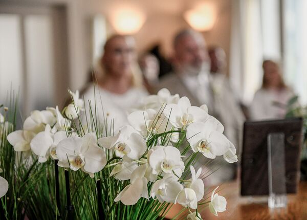 Blumen im Vordergrund scharf und das Brautpaar im Hintergrund unscharf. Aufgenommen im Kieler Standesamt.