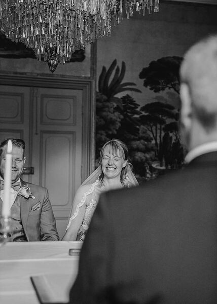 Braut lacht spontan während der Trauung und hat dabei die Augen zu geschlossen.