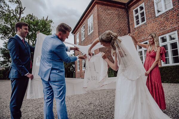 Brautpaar schneidet ein Herz aus, welches auf ein Bettlaken gemalt wurde.