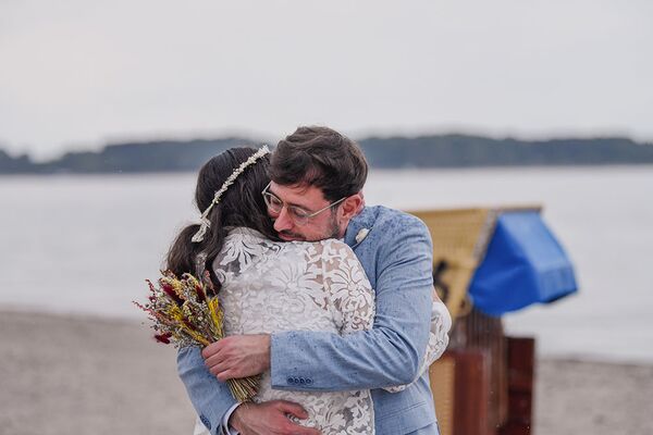Brautpaar umarmt sich bei einem Fotoshooting am Strand in Laboe.