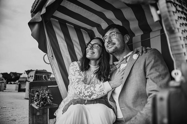 Hochzeitsfotografie Kiel - Brautpaar sitzt im Strandkorb und schaut in die Ferne.