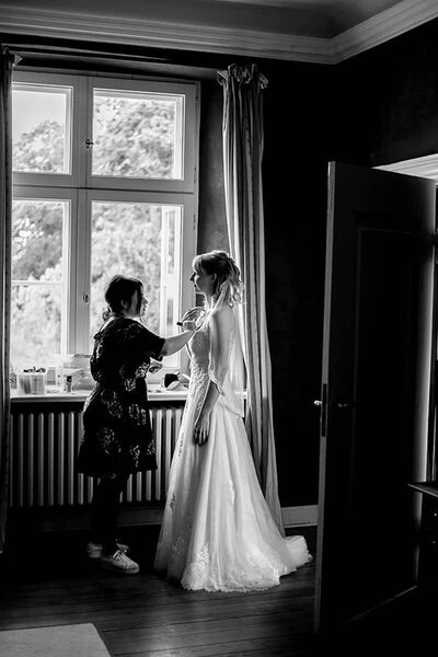 Braut wird von Visagistin am Dekolleté abgepudert.